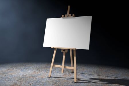 Wooden Artist Easel with White Mock Up Canvas in the volumetric light on a black background. 3d Rendering.の写真素材