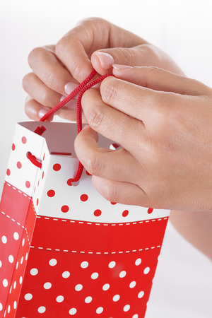 Woman Hand Holding Red Gift Bag with Present on a white backgroundの写真素材