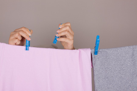 Woman Hands Hanging Wet Clean Cloth To Dry On Clothes Line At Laundry Room on a grey backgroundの写真素材