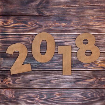 Cardstock Numbers 2018 Happy New Year Sign over wooden table background. 3d Rendering