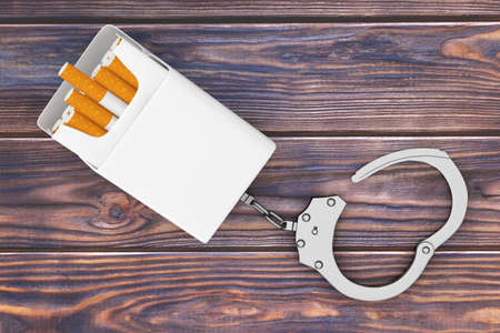 Mockup Blank Cigarettes Pack Chained to Metal Handcuffs on a wooden table background. 3d Renderingの写真素材