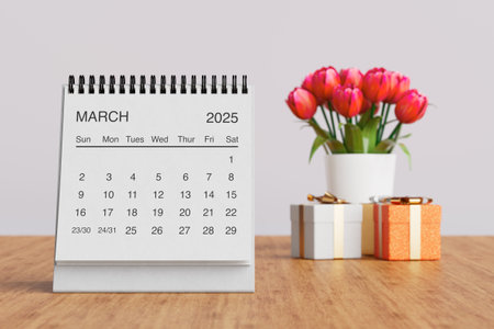 White Desk Monthly March 2025 Business Calendar Near Tulips Flowers and Gift Boxes on a white background. 3d renderingの写真素材