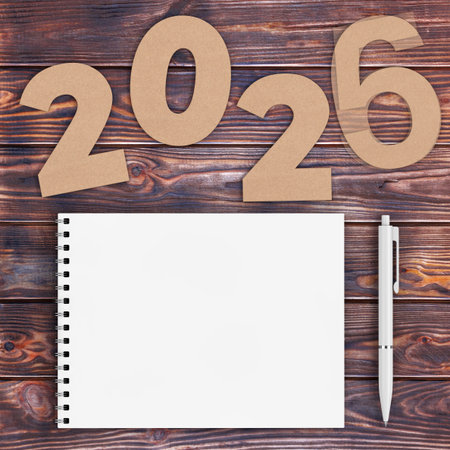 Cardstock Numbers 2026 Happy New Year Sign near White Spiral Paper Cover Notebook with Pen over...