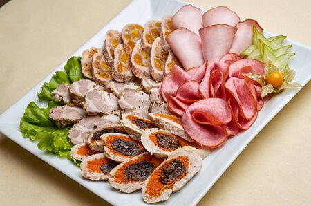 Assorted meat rolls on white dish decorated with greensの写真素材