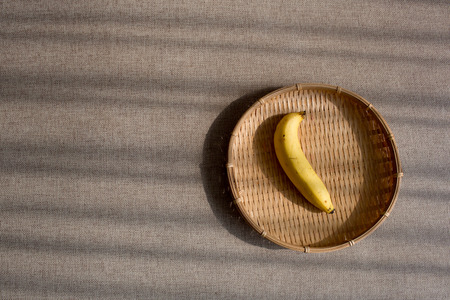 Banana on the basketwork with light and shadowの写真素材