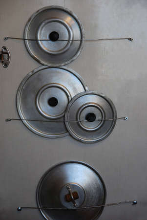 Hanging steel Pot's covers on a wood wallの写真素材