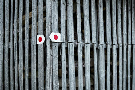 Red circle on a white background with an arrow. Tourist sign, tourist mark sprayed, painted on a wooden fence in Bavaria, Germany. Colorful signs for hiking, turistic route for nature-lover backpackerの写真素材