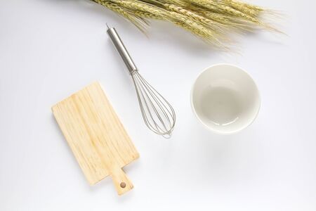Wooden chopping board,whisk and white bowl on white background