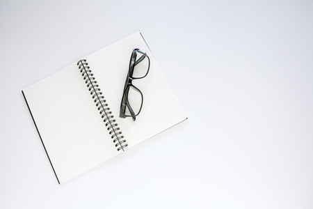 Notebook and glasses on white background.の写真素材