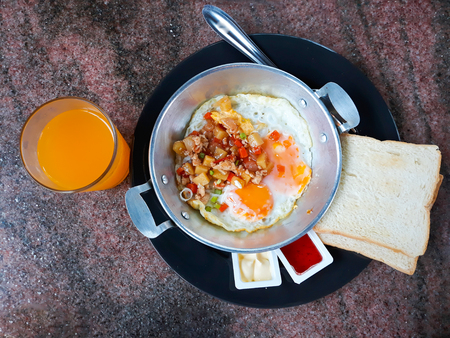 Pan-fried egg with toppings ,bread and orange juice.の写真素材