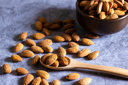Almonds with wooden bowl and spoon on the dark table.の写真素材