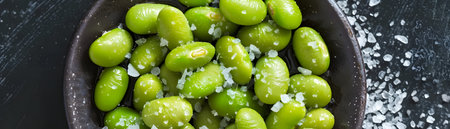 Vibrant green edamame beans a protein rich legume are featured in this healthy snack or appetizer image The edamame are presented in a simple bowl or plate setting with a light dusting of sea saltの素材