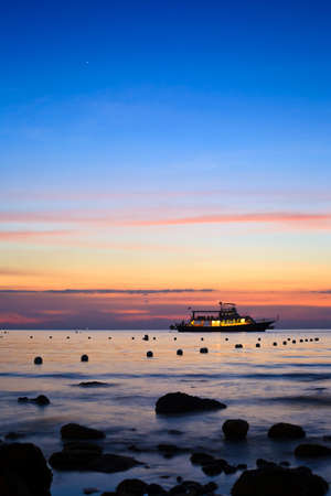 sunset and boat in the middle of sea with highlight skyの写真素材