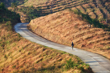walking across curve road in mountain aloneの写真素材