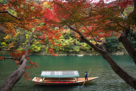 Boatman punting the boat at river. Arashiyama in autumn season along the river in Kyoto, Japan.の写真素材
