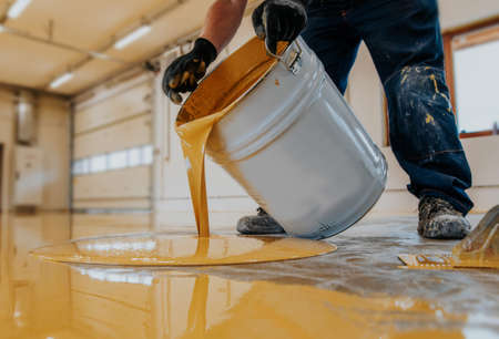 Worker applying a yellow epoxy resin bucket on floor.の写真素材