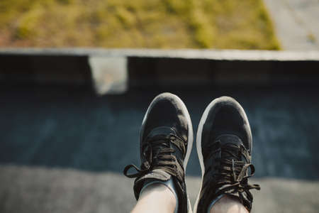 Hiker's legs hanging over the edge of a high buildingの写真素材