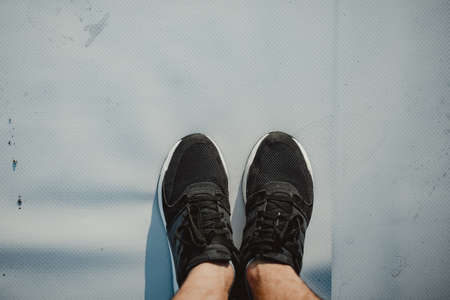 Hiker's legs hanging over the edge of a high building