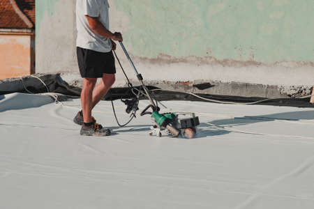Worker welding pvc roof membrane by heater with welder machineの写真素材