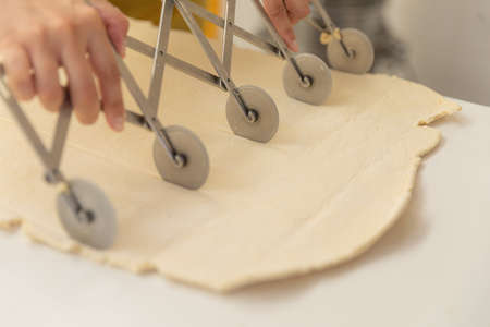 Baker hands using dough slicers for cutting equal portions of dough for preparation of pastry...