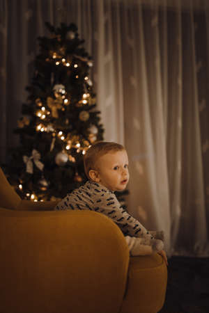 Merry Christmas and Happy Holidays! Child looks curiously at the lights in the holiday decorの写真素材