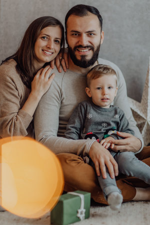 Young beautiful father and mother with baby in christmas decor studio having fun.の写真素材