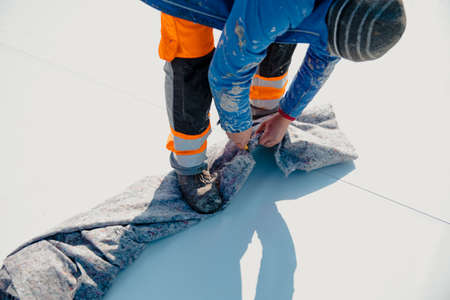 Worker prepares geotextile for the roof, covers it with synthetic PVC membraneの写真素材