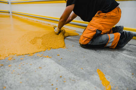 Worker applying epoxy and polyurethane flooring system.These easy-to-clean products also have non-slip features.の写真素材