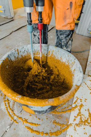 Photo in motion with a worker mixing colored polyurethane mortar with epoxy resin