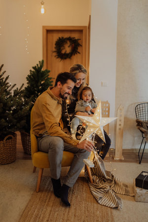 The little girl held in her father's arms is playing with a light from a Christmas decorationの写真素材