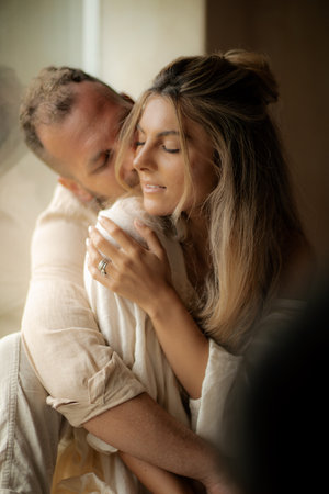 Beautiful couple in love embracing and kissing in the room at homeの写真素材