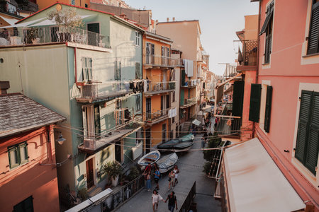 This narrow street, with its picturesque and colorful houses, is heavily frequented by tourists in the charming town of Manarola.の写真素材