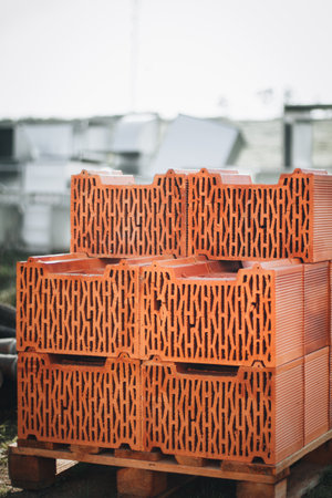 A pile of bricks has been stacked neatly on a wooden pallet at a construction site, ready for use in building projects.の写真素材