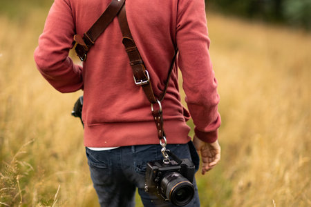 Photographer with camera in the field. Close up of male hands holding camera.の写真素材