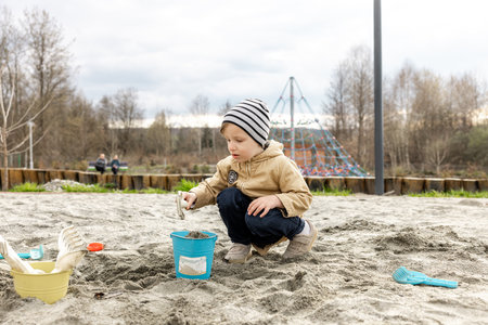Cute little boy playing with sand on the playground in springtimeの写真素材