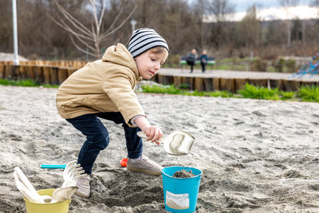 Cute little boy playing with sand and toys in garden on spring dayの写真素材