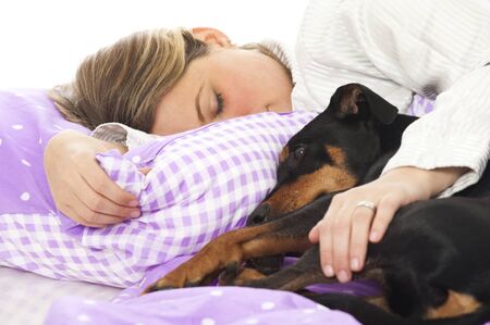 Woman lying in bed with dogの写真素材