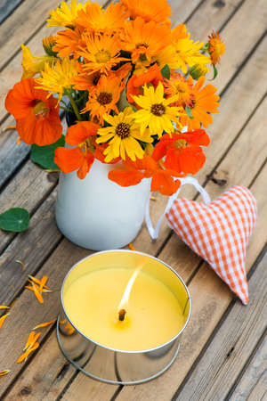 Marigolds and nasturtiums in an old cup on a tableの写真素材