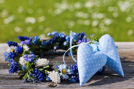 Spring flower wreath with hearts on wooden background