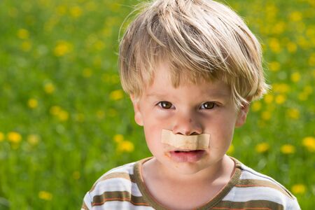 Little boy with a plaster over your mouth