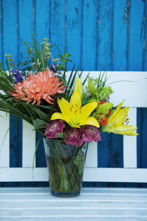 Beautiful flower bouquet with lily and other flowers on a garden bench
