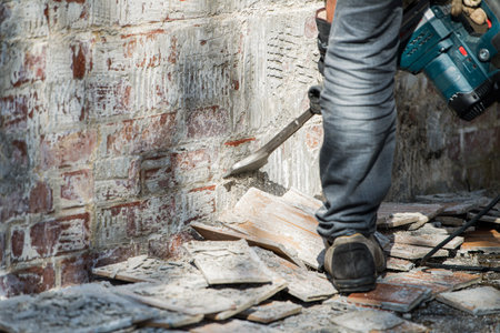 Man removes tiles from a wall with a hammer drillの写真素材