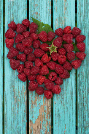 raspberries placed as a heart on a garden table