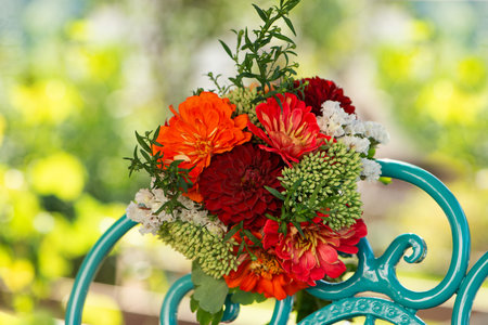 Colorful flower bouquet with dalias on a romantic garden chair with copy spaceの写真素材