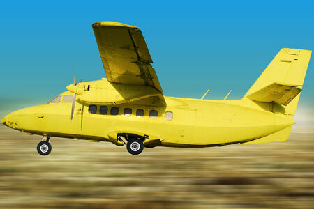 Yellow retro aircraft on the background of blue sky and fieldsの写真素材