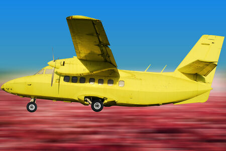 Yellow retro aircraft on the background of blue sky and fieldsの写真素材