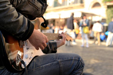 A street musician plays guitar on the squareの写真素材