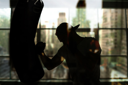 Boxer hits a punching bag against the window, trainingの写真素材