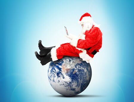 Santa Claus sitting with laptop on the planetの写真素材