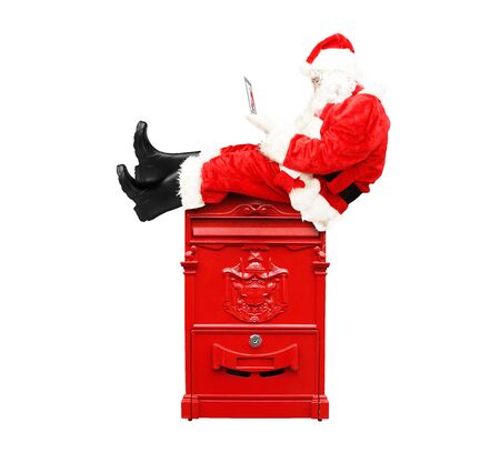 Santa Claus sitting with laptop on the mailboxの写真素材